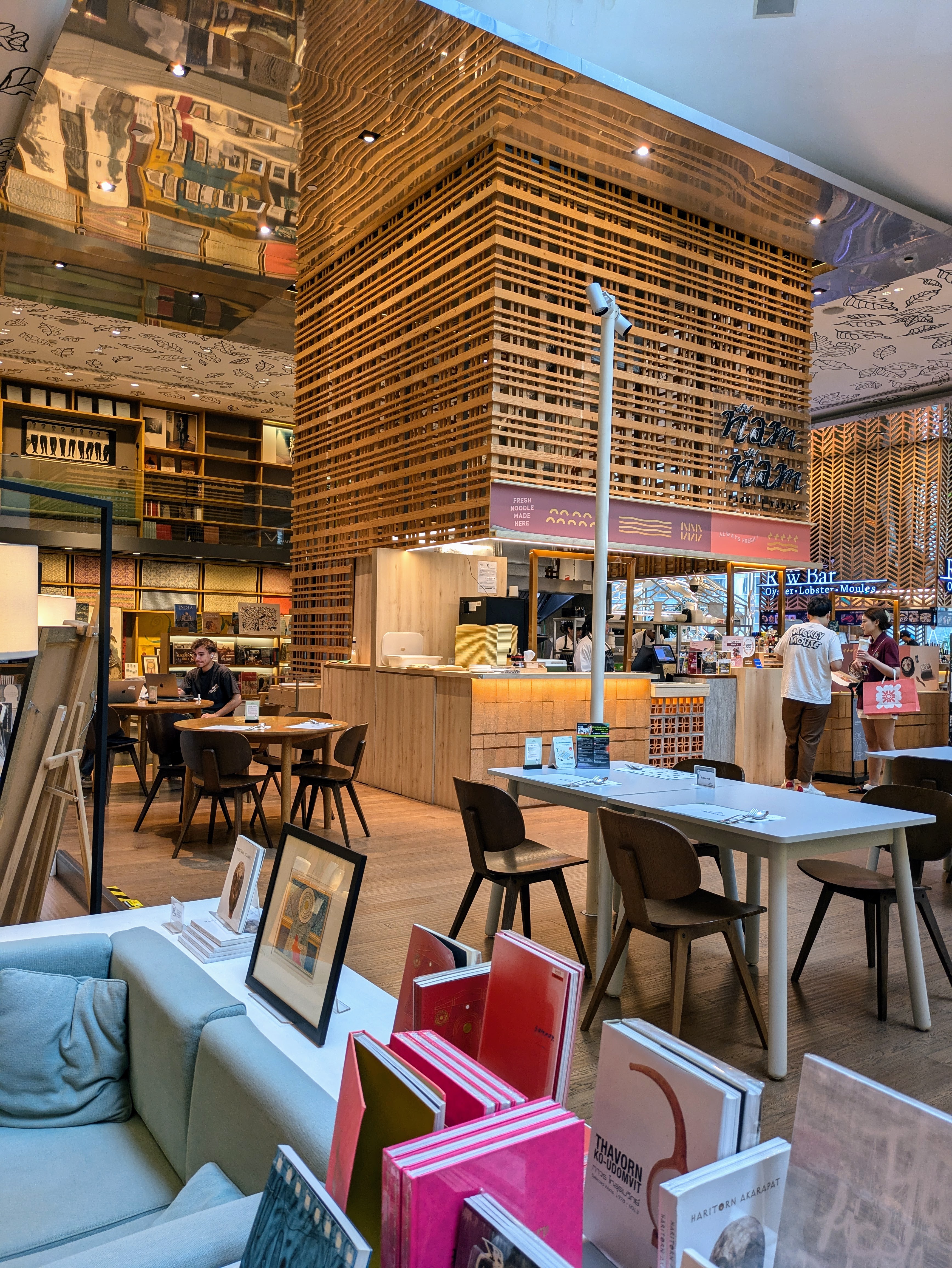 Espacio abierto con libros y zonas para sentarse y trabajar en Open House Bangkok